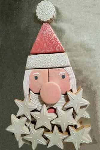 Cookies on a plate arranged to resemble Santa's face, with a beard made out of stars, a hat, and a face.