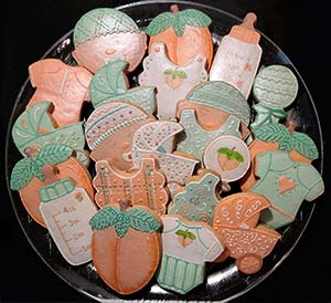 Baby cookie tray: Babies, onesies, peaches, bibs, rattles, bottles, and baby carriage.