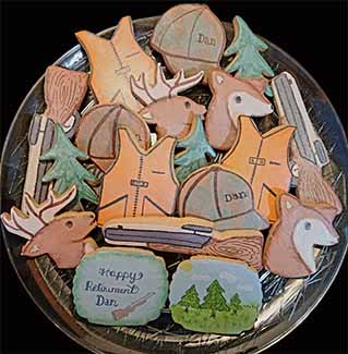 Retirement cookie tray: Hunting rifle, vest and cap, deer and trees.